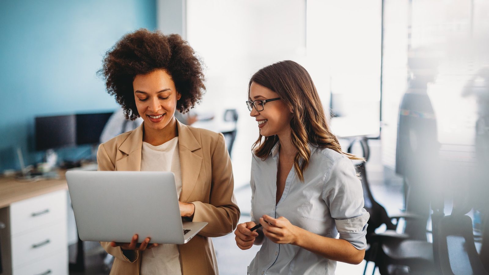 Duas colegas de trabalho conferindo juntas um notebook no escritório